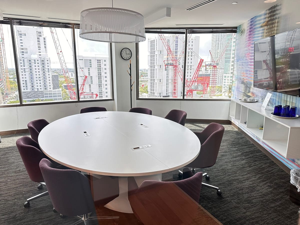 Conference room with a round table and floor-to-ceiling windows over Miami